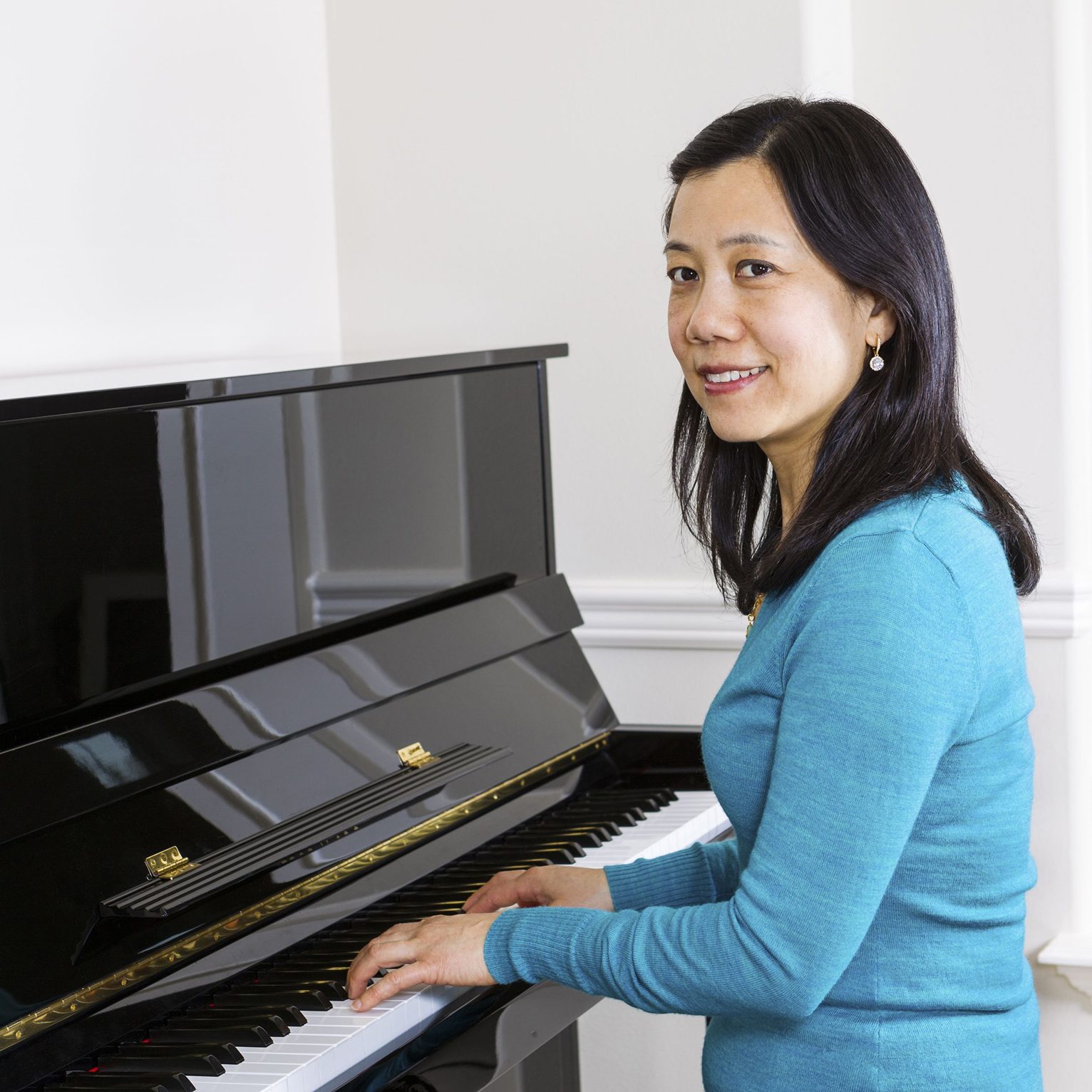 18286242 - vertical photo of mature woman playing piano with white walls in background